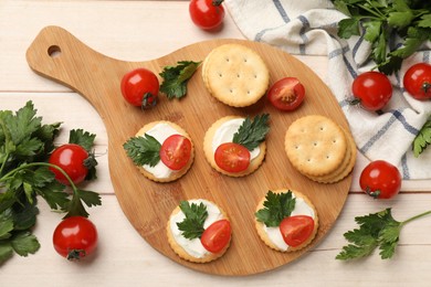 Photo of Tasty crackers with cream cheese, tomatoes and parsley on white wooden table, flat lay