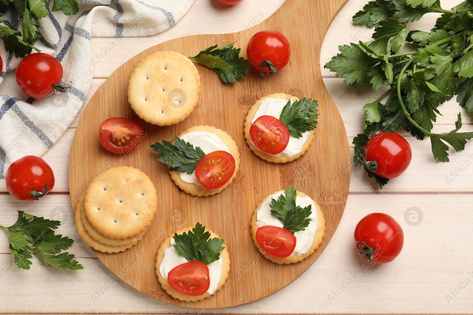 Photo of Tasty crackers with cream cheese, tomatoes and parsley on white wooden table, flat lay