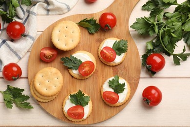 Photo of Tasty crackers with cream cheese, tomatoes and parsley on white wooden table, flat lay