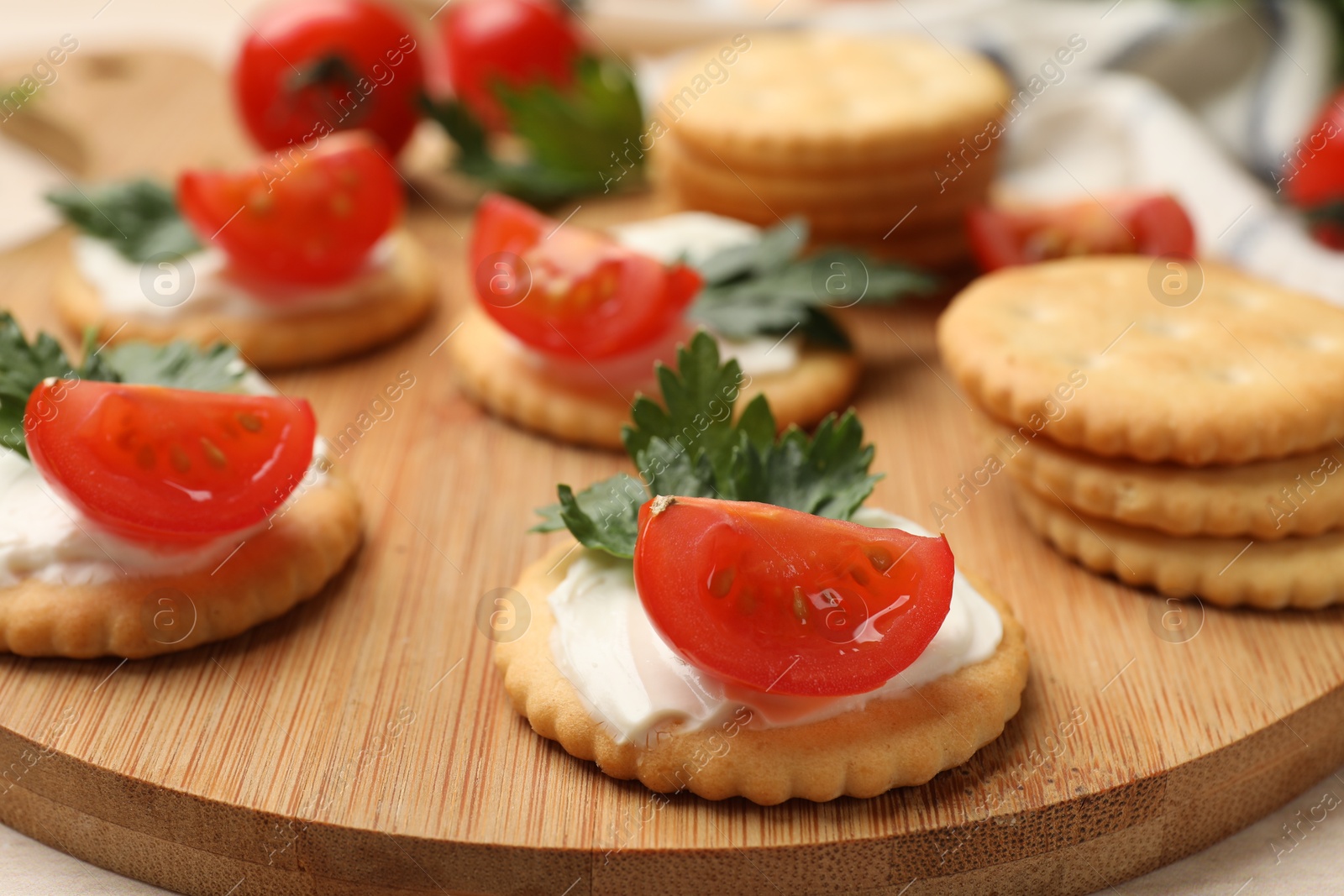 Photo of Tasty crackers with cream cheese, tomatoes and parsley on white wooden table, closeup