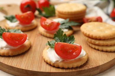 Photo of Tasty crackers with cream cheese, tomatoes and parsley on white wooden table, closeup