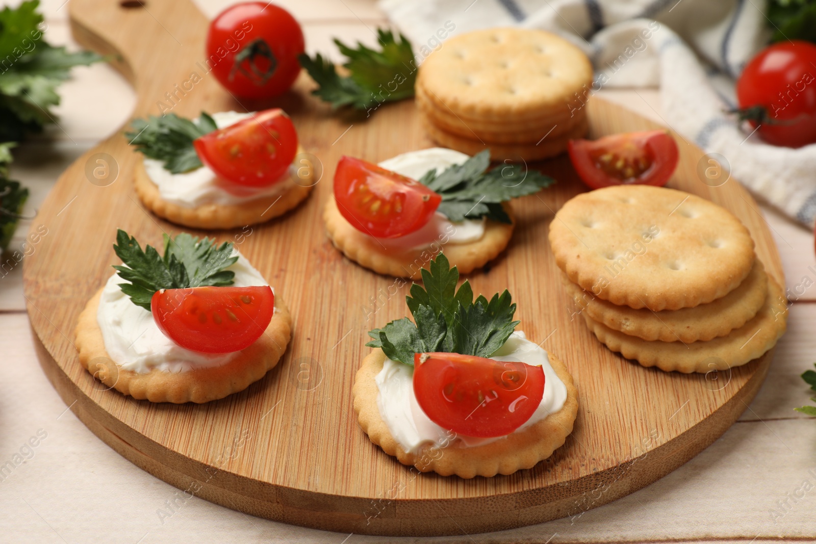Photo of Tasty crackers with cream cheese, tomatoes and parsley on white wooden table, closeup