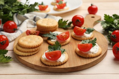 Photo of Tasty crackers with cream cheese, tomatoes and parsley on white wooden table, closeup