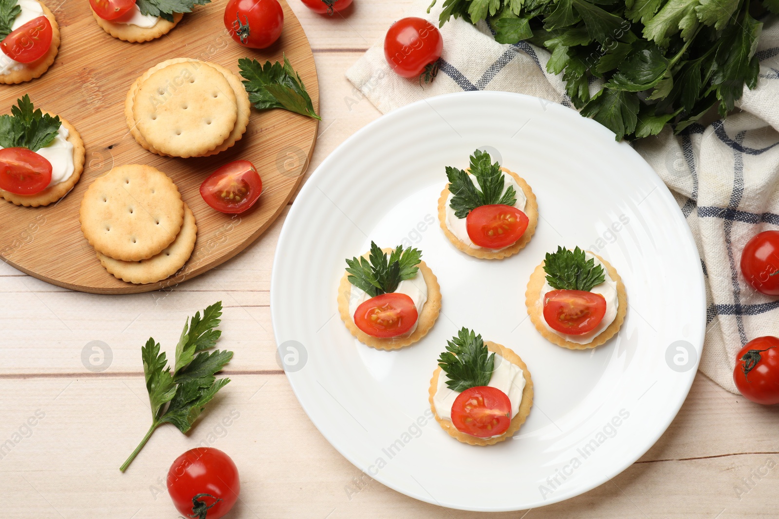 Photo of Tasty crackers with cream cheese, tomatoes and parsley on white wooden table, flat lay