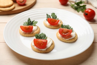 Photo of Tasty crackers with cream cheese, tomatoes and parsley on white wooden table, closeup