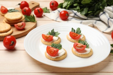 Photo of Tasty crackers with cream cheese, tomatoes and parsley on white wooden table, closeup