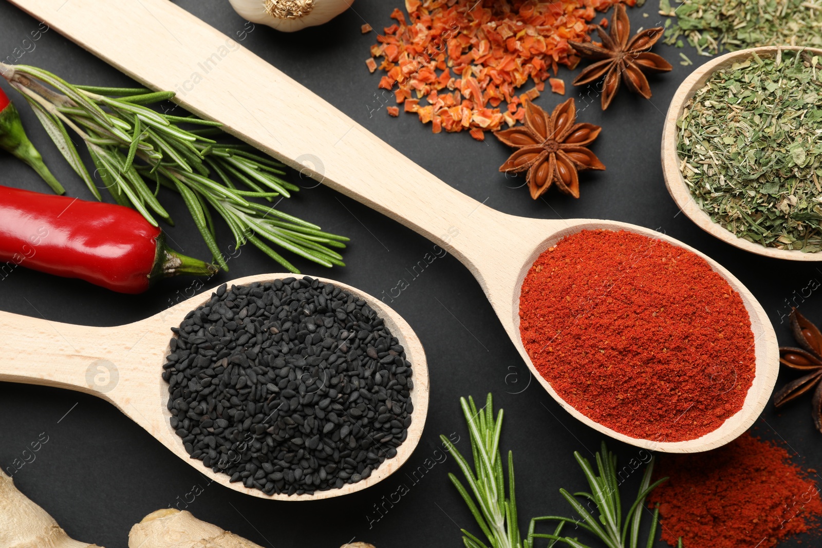 Different aromatic spices in spoons on black table, flat lay Photo of Different aromatic spices in spoons on black table, flat lay