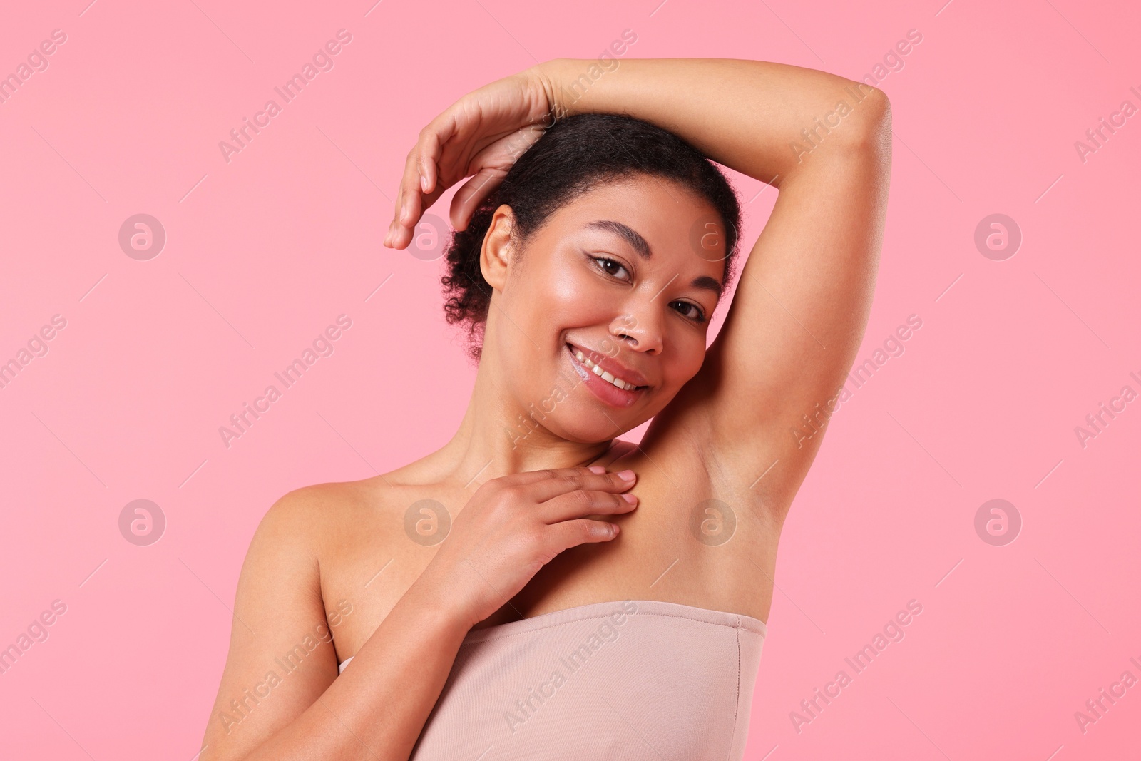 Photo of Woman showing hairless armpit after epilation procedure on pink background