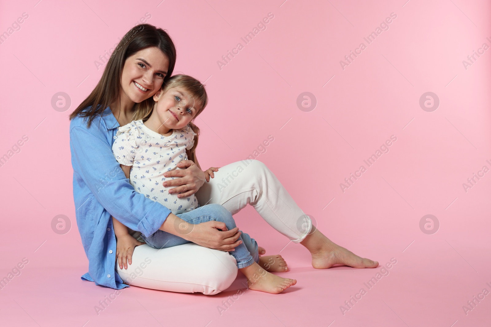 Happy mother and her cute daughter on pink background Photo of Happy mother and her cute daughter on pink background