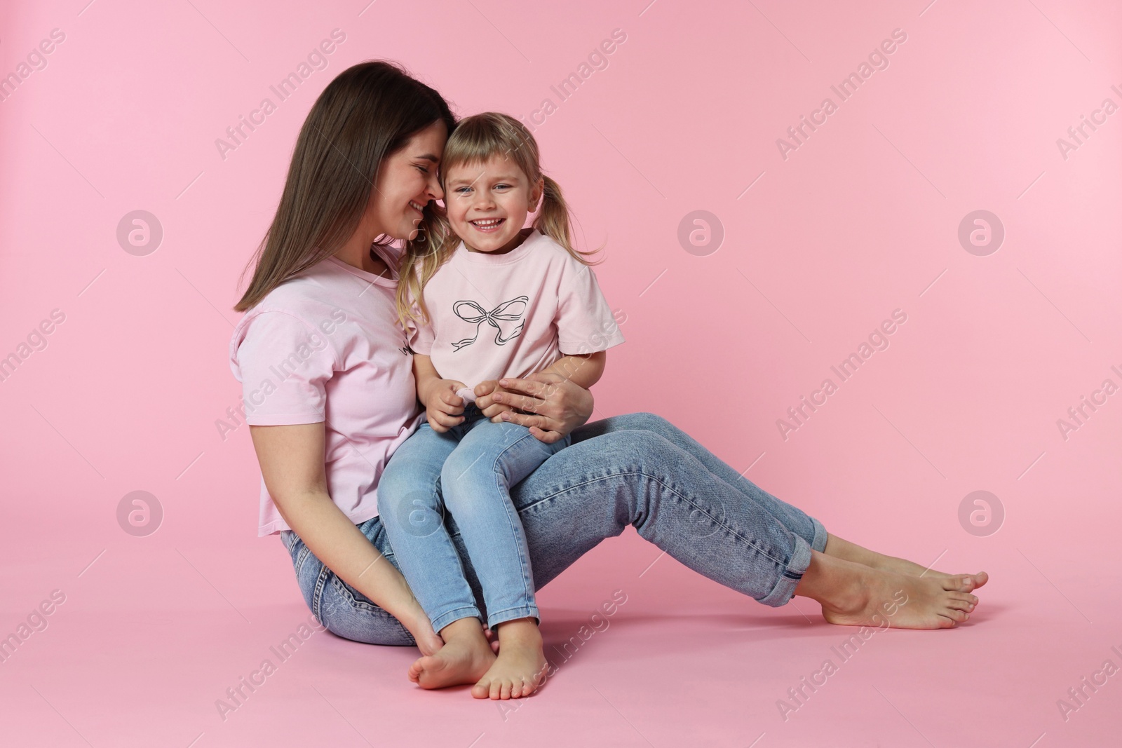 Happy mother and her cute daughter on pink background Photo of Happy mother and her cute daughter on pink background