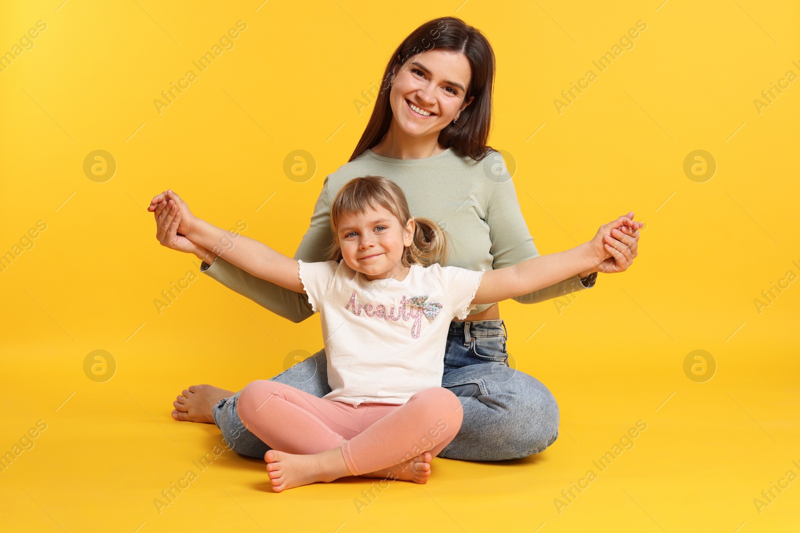 Photo of Happy mother and her cute daughter on orange background
