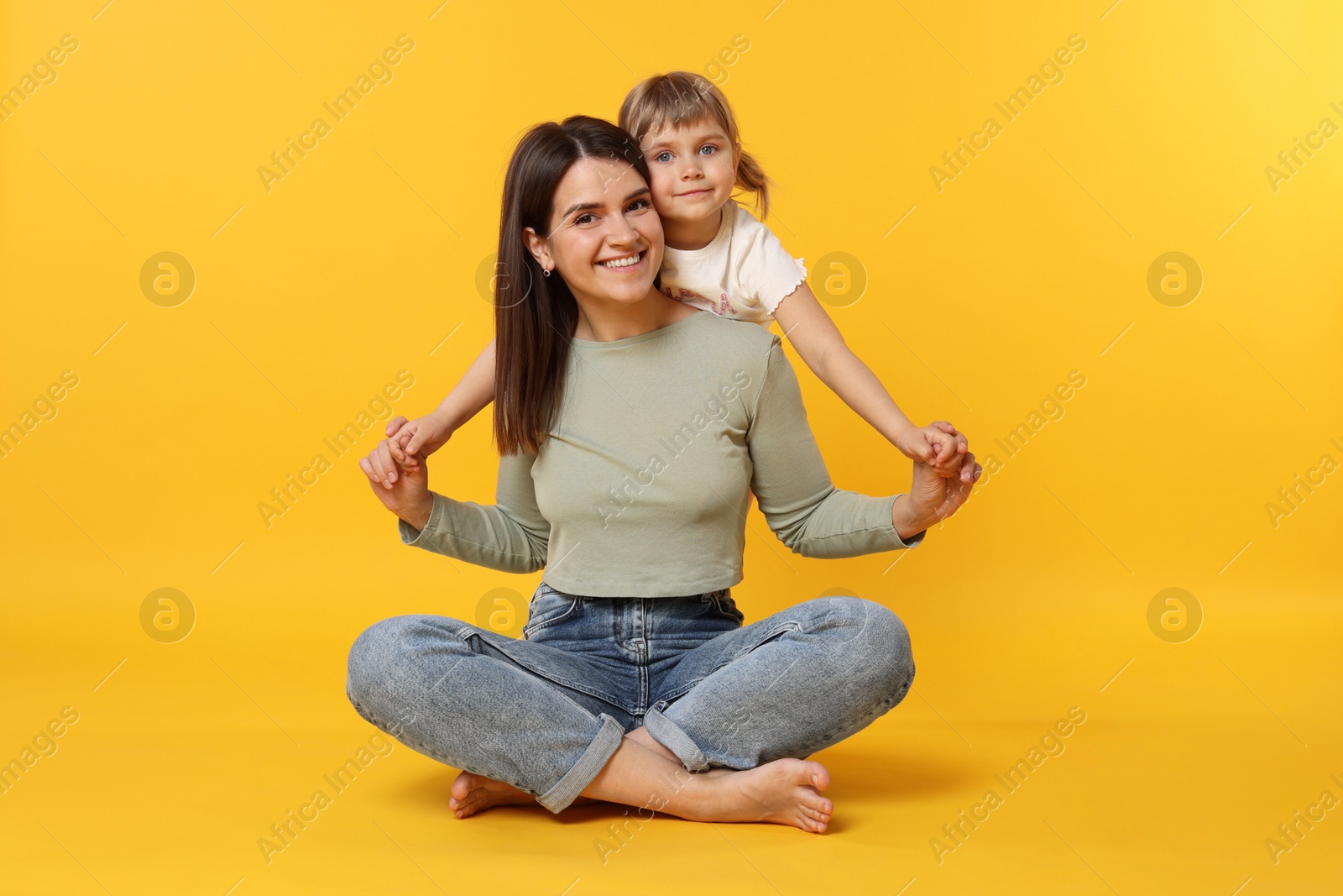 Happy mother and her cute daughter on orange background Photo of Happy mother and her cute daughter on orange background