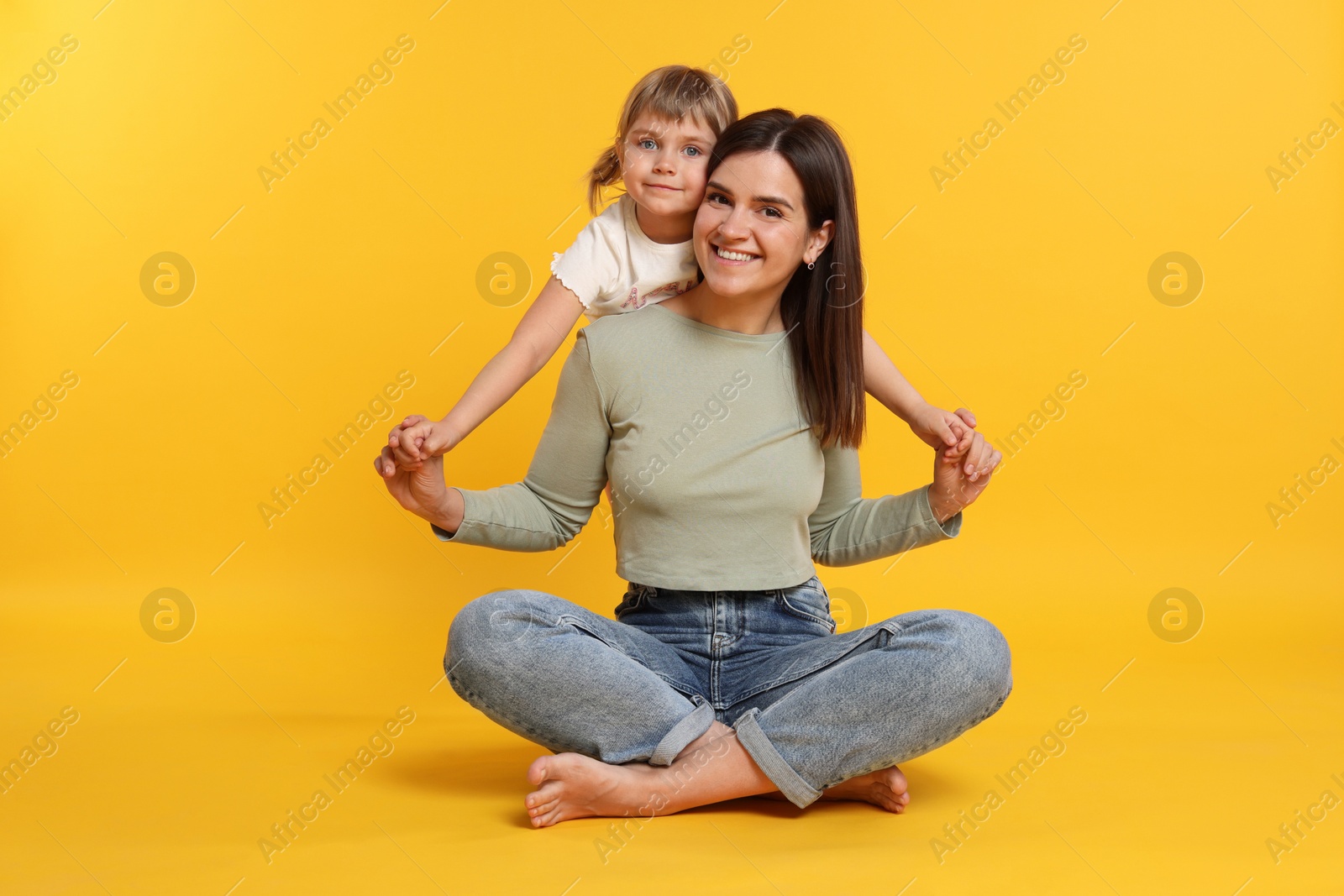 Photo of Happy mother and her cute daughter on orange background