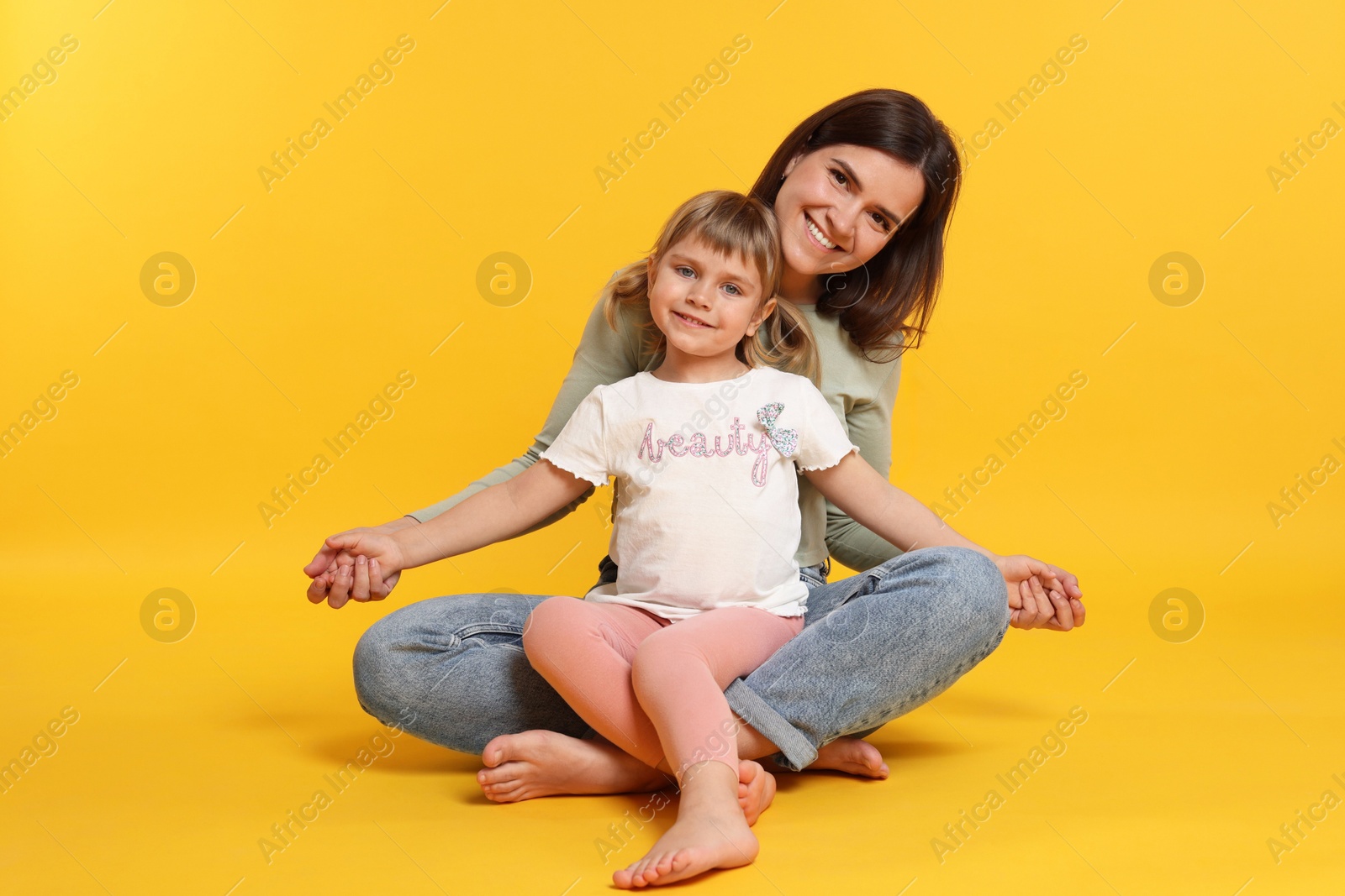 Photo of Happy mother and her cute daughter on orange background