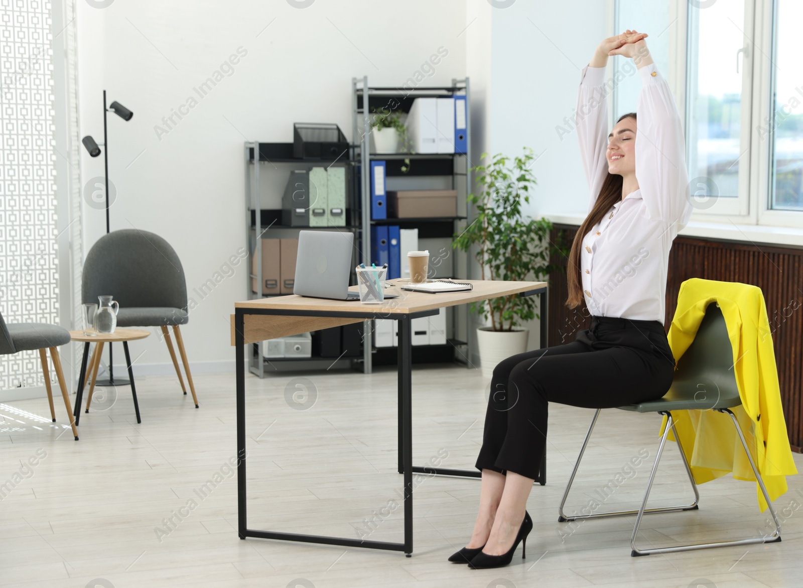 Photo of Beautiful woman stretching on chair in office