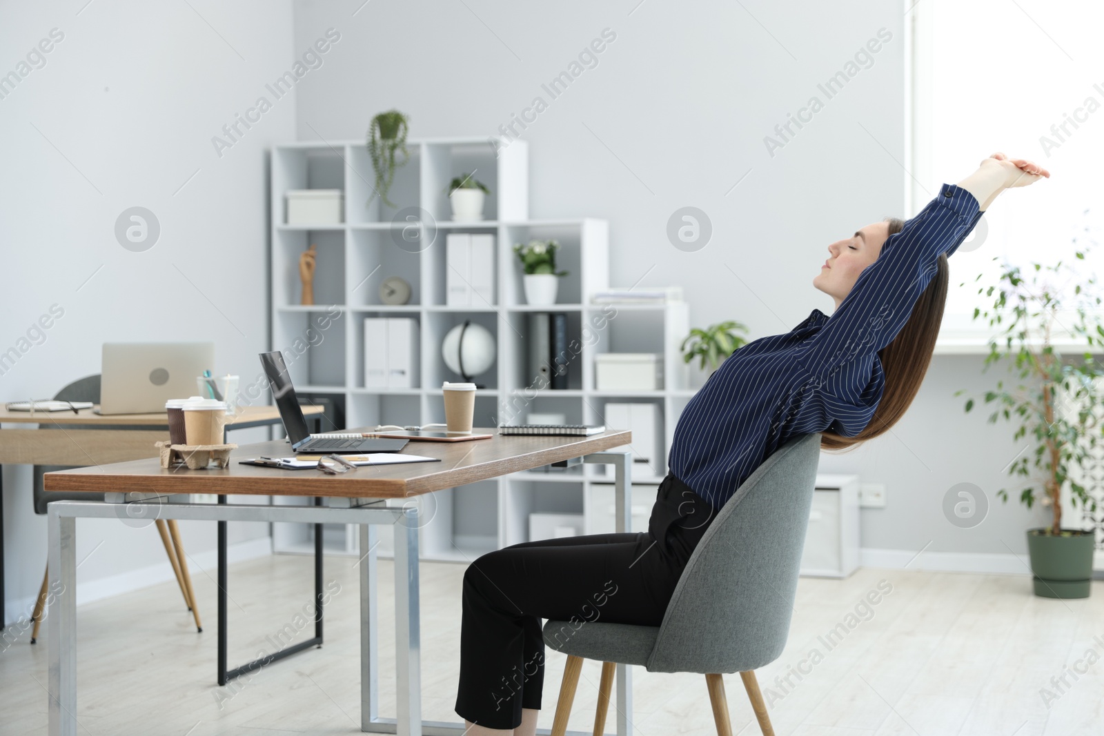 Beautiful woman stretching on chair in office Photo of Beautiful woman stretching on chair in office