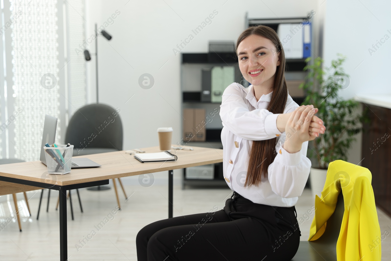 Photo of Beautiful woman stretching on chair in office