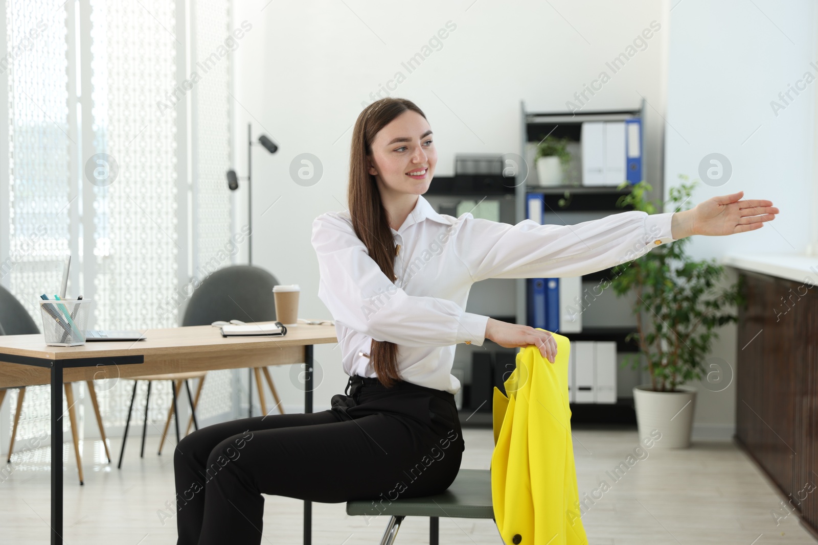 Photo of Beautiful woman stretching on chair in office
