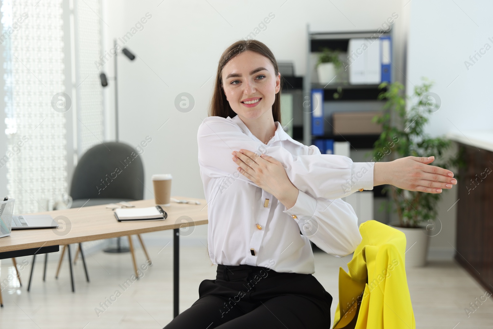 Beautiful woman stretching on chair in office Photo of Beautiful woman stretching on chair in office