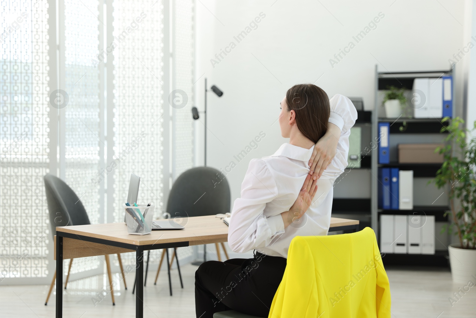 Photo of Young woman stretching on chair in office