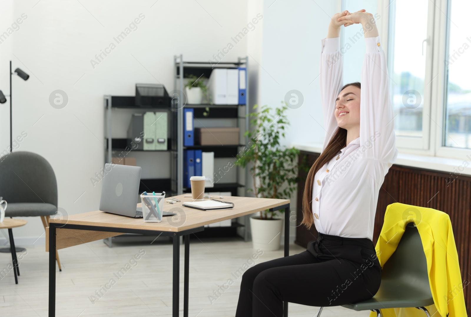 Photo of Beautiful woman stretching on chair in office