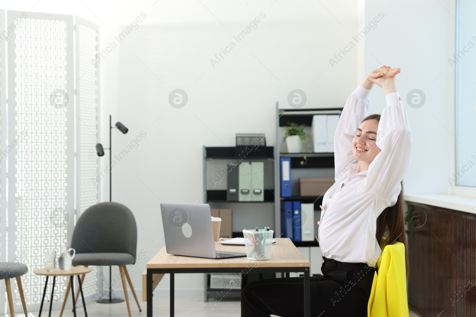 Beautiful woman stretching on chair in office Photo of Beautiful woman stretching on chair in office