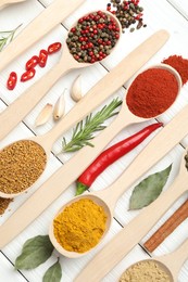 Photo of Different aromatic spices in spoons on white wooden table, flat lay
