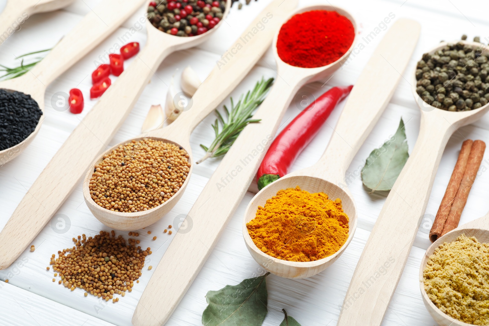 Different aromatic spices in spoons on white wooden table, closeup Photo of Different aromatic spices in spoons on white wooden table, closeup