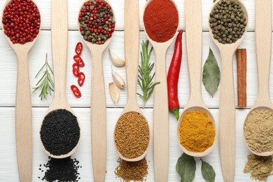 Photo of Different aromatic spices in spoons on white wooden table, flat lay