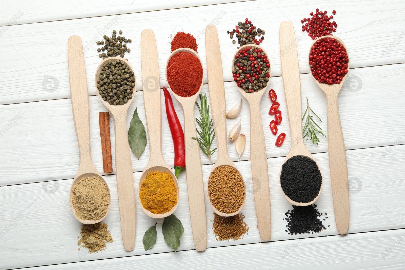 Different aromatic spices in spoons on white wooden table, flat lay Photo of Different aromatic spices in spoons on white wooden table, flat lay