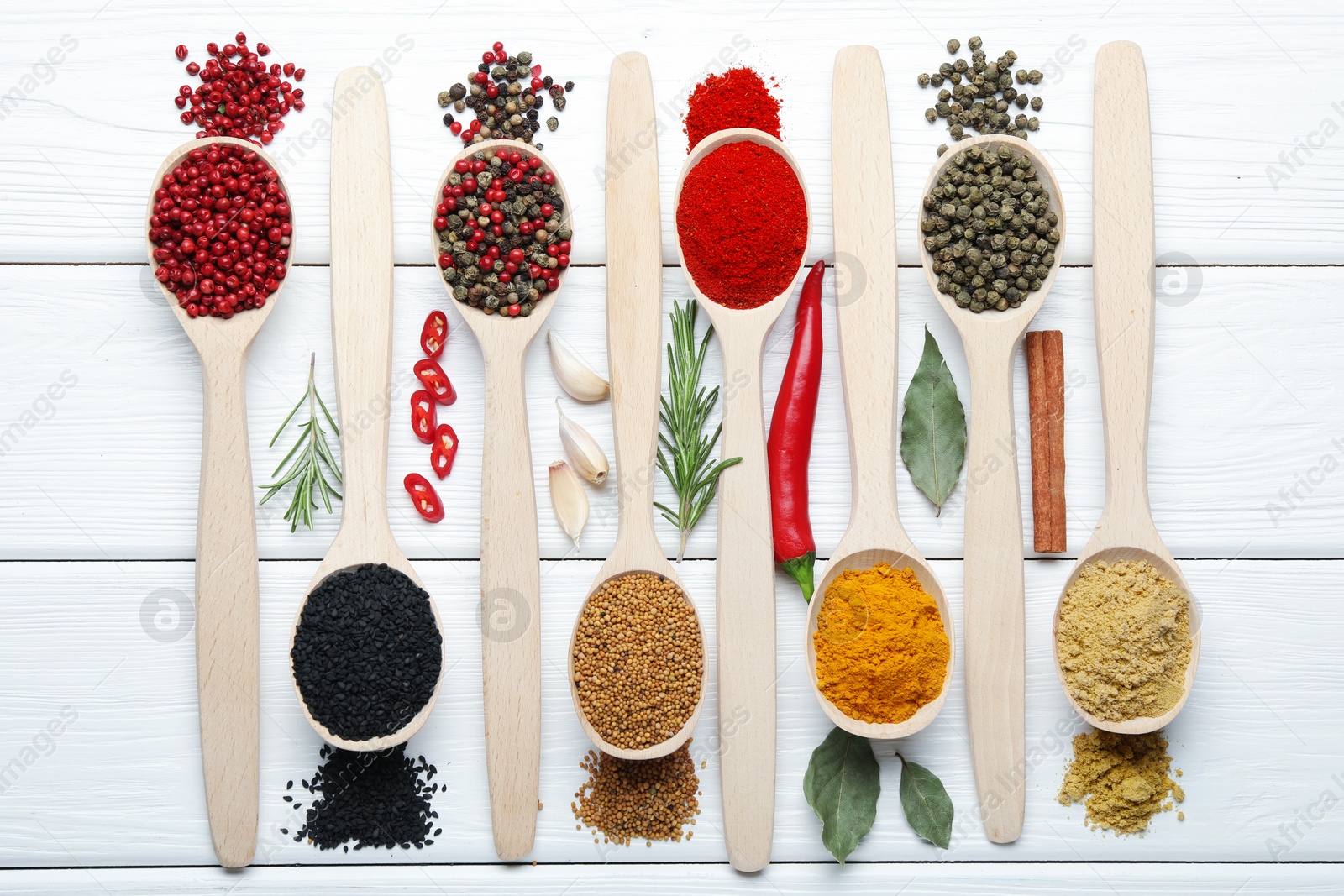Different aromatic spices in spoons on white wooden table, flat lay Photo of Different aromatic spices in spoons on white wooden table, flat lay
