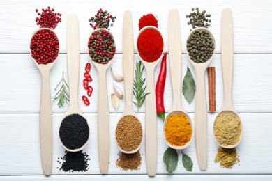 Photo of Different aromatic spices in spoons on white wooden table, flat lay