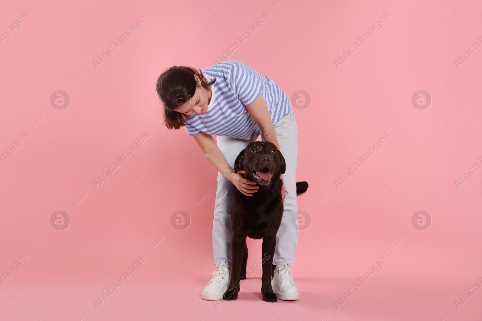 Animal training. Woman with her cute dog on pink background Photo of Animal training. Woman with her cute dog on pink background