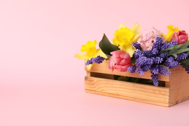 Photo of Beautiful colorful flowers in crate on pink background. Space for text