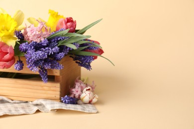 Photo of Beautiful colorful flowers in crate on beige background. Space for text