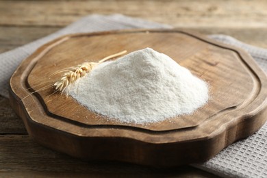 Photo of Wheat flour and spikelet on wooden table, closeup