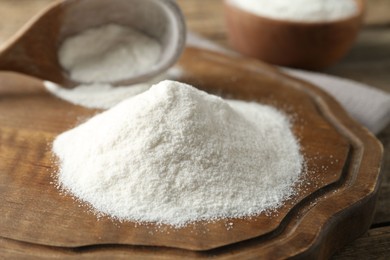 Photo of Wheat flour and spoon on wooden table, closeup