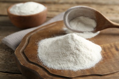Photo of Wheat flour and spoon on wooden table, closeup