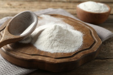 Photo of Wheat flour and spoon on wooden table, closeup