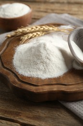 Photo of Wheat flour and spikelets on wooden table, closeup