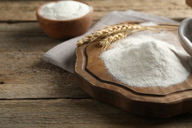 Photo of Wheat flour and spikelets on wooden table, closeup