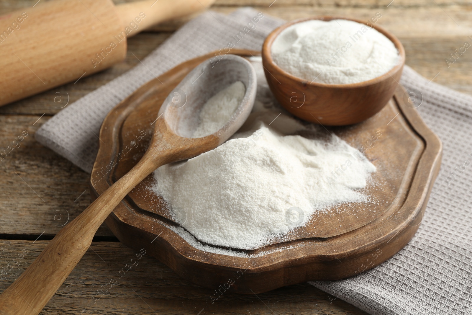 Wheat flour, spoon and rolling pin on wooden table, closeup Photo of Wheat flour, spoon and rolling pin on wooden table, closeup