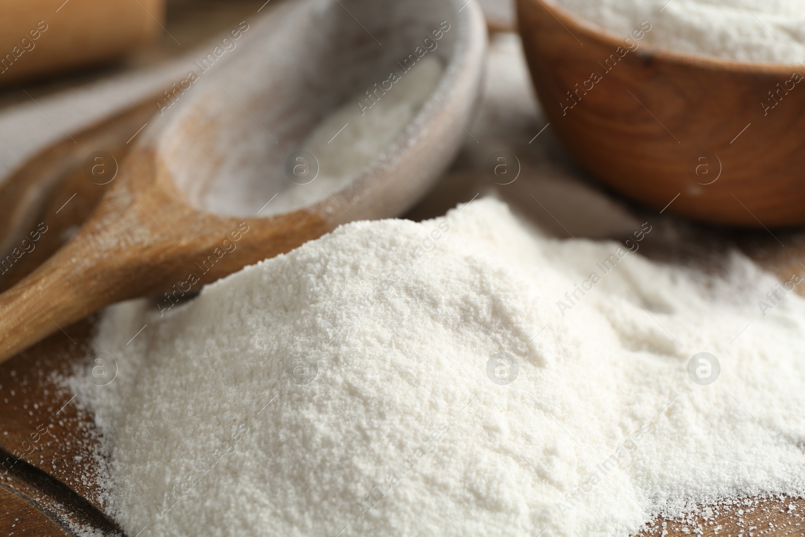 Wheat flour and spoon on wooden board, closeup Photo of Wheat flour and spoon on wooden board, closeup