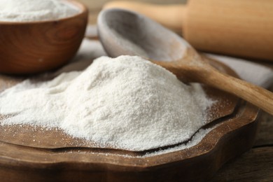 Photo of Wheat flour and spoon on wooden table, closeup