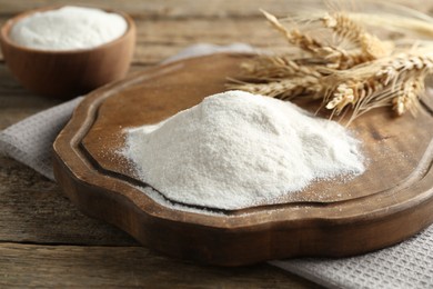 Photo of Wheat flour and spikelets on wooden table, closeup
