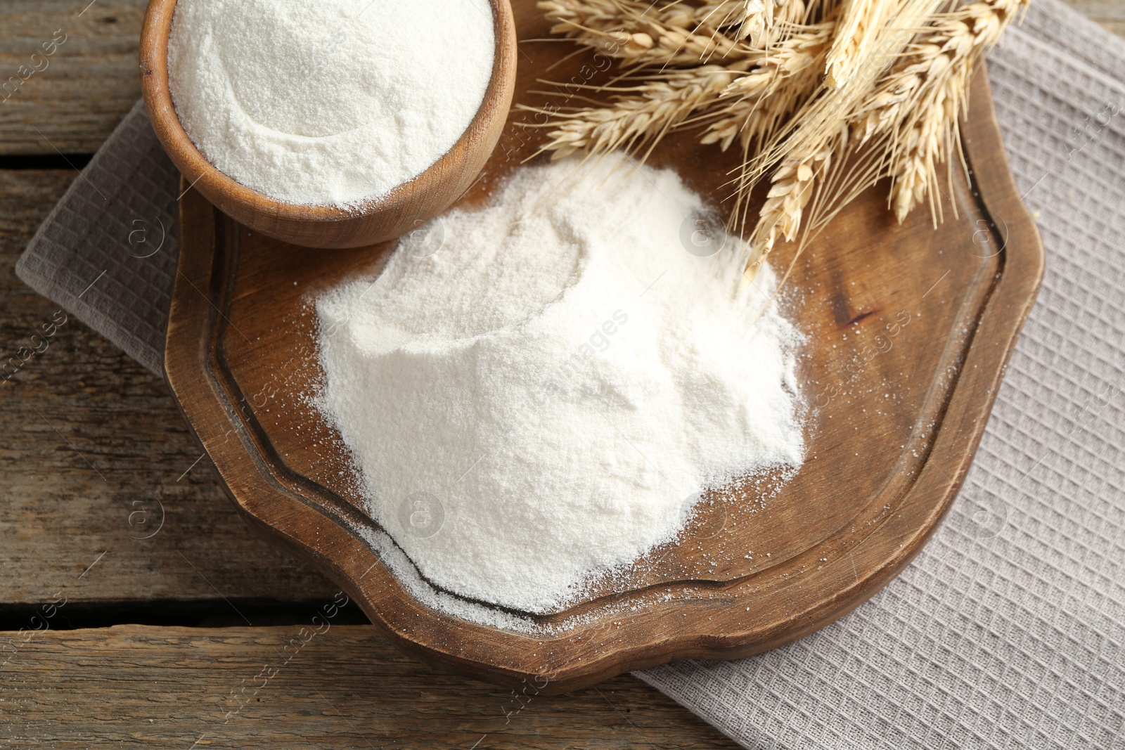 Wheat flour and spikelets on wooden table, top view Photo of Wheat flour and spikelets on wooden table, top view