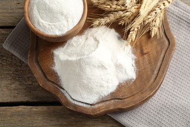 Photo of Wheat flour and spikelets on wooden table, top view
