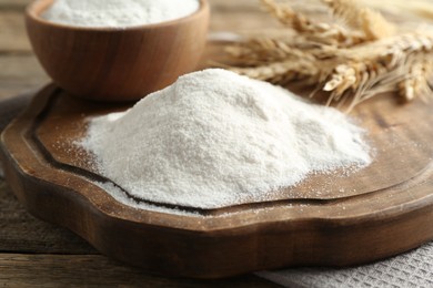 Photo of Wheat flour and spikelets on wooden table, closeup