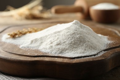 Photo of Flour and wheat spikelet on wooden board, closeup