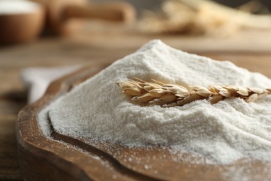 Photo of Wheat flour and spikelet on wooden table, closeup